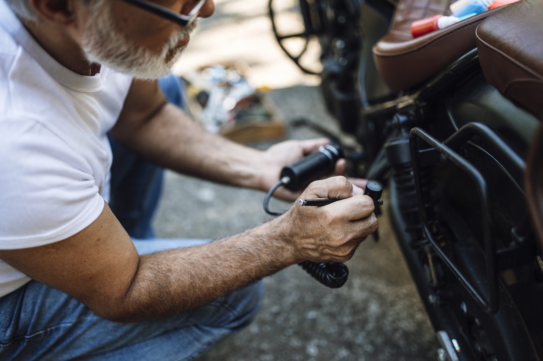 mécanicien penché sur une moto, en train d'intervenir sur la mécanique