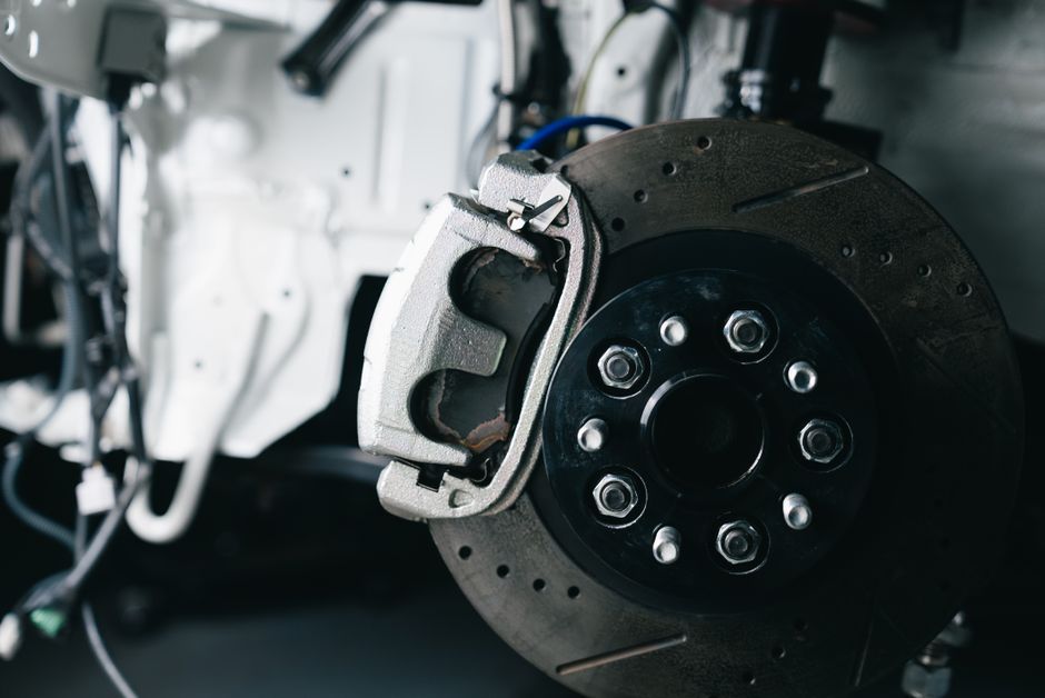 Detailed view of a car&rsquo;s brake caliper and disc in a workshop setting.
